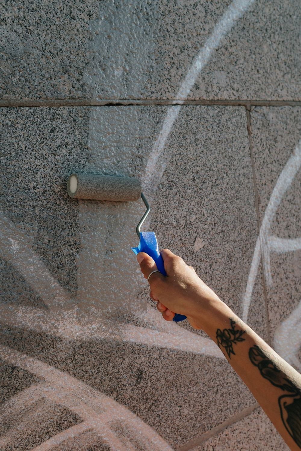 Valjak prelazi preko grafita na betonskom zidu